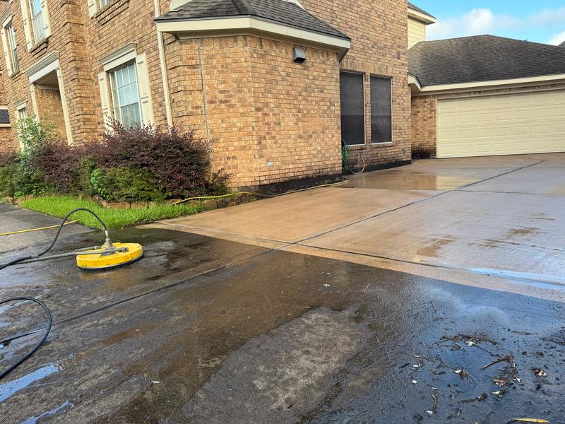 Driveway half cleaned: the far side is clean, the near side still dark, with ACE's surface cleaner on it.